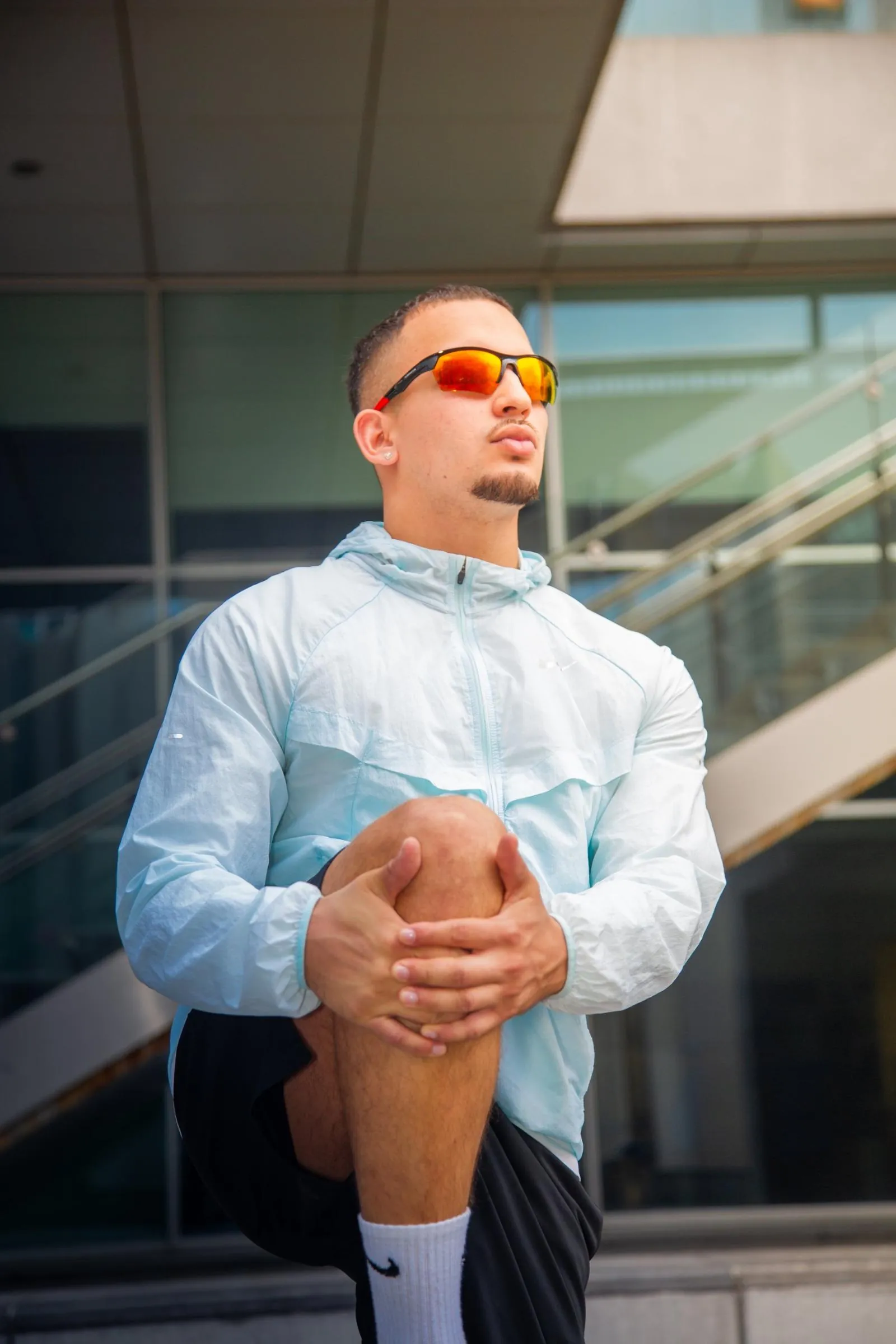 Runner in sunglasses stretching his leg